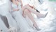 A woman in a wedding dress sitting on a chair.