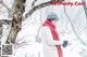 A woman in a white coat and red scarf holding a snow globe.